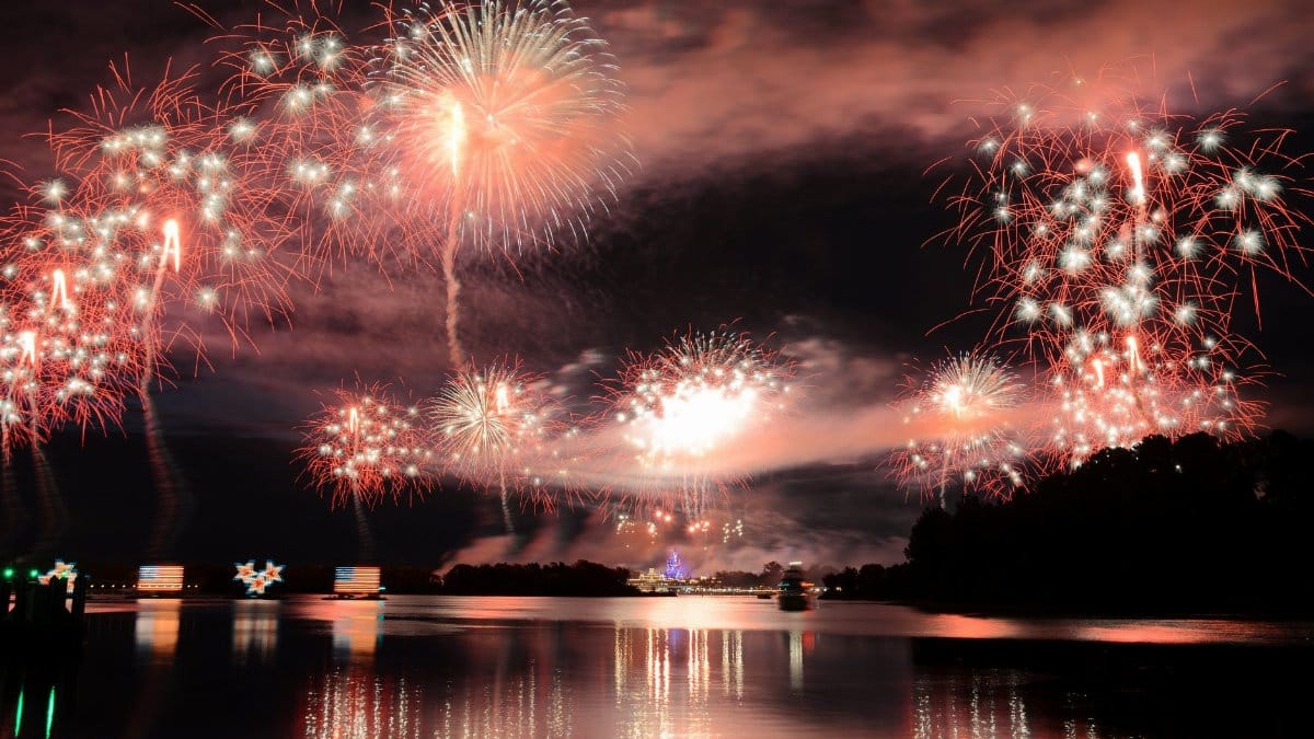 Dazzling fireworks light up the night sky over Lake Buena Vista, FL, creating a stunning reflection on the water.