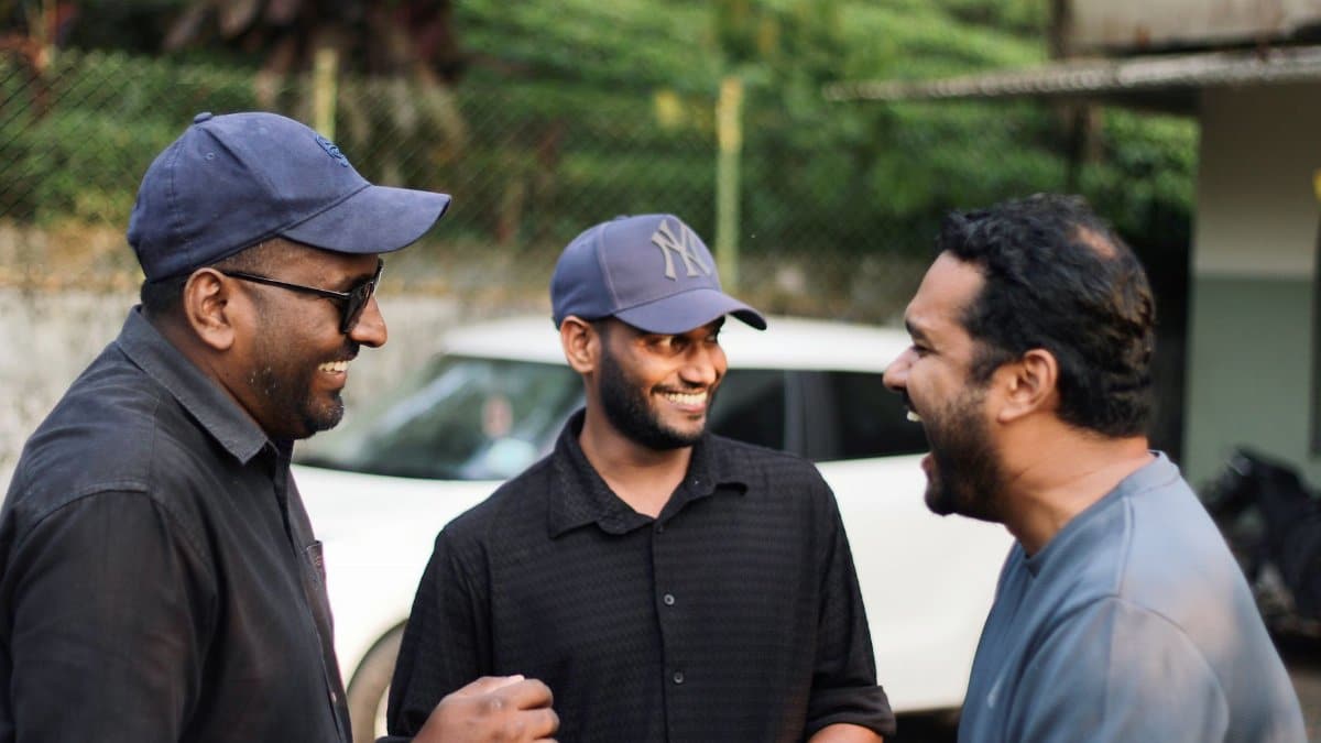 Three men enjoy a shared moment of laughter outdoors, capturing camaraderie in natural light.