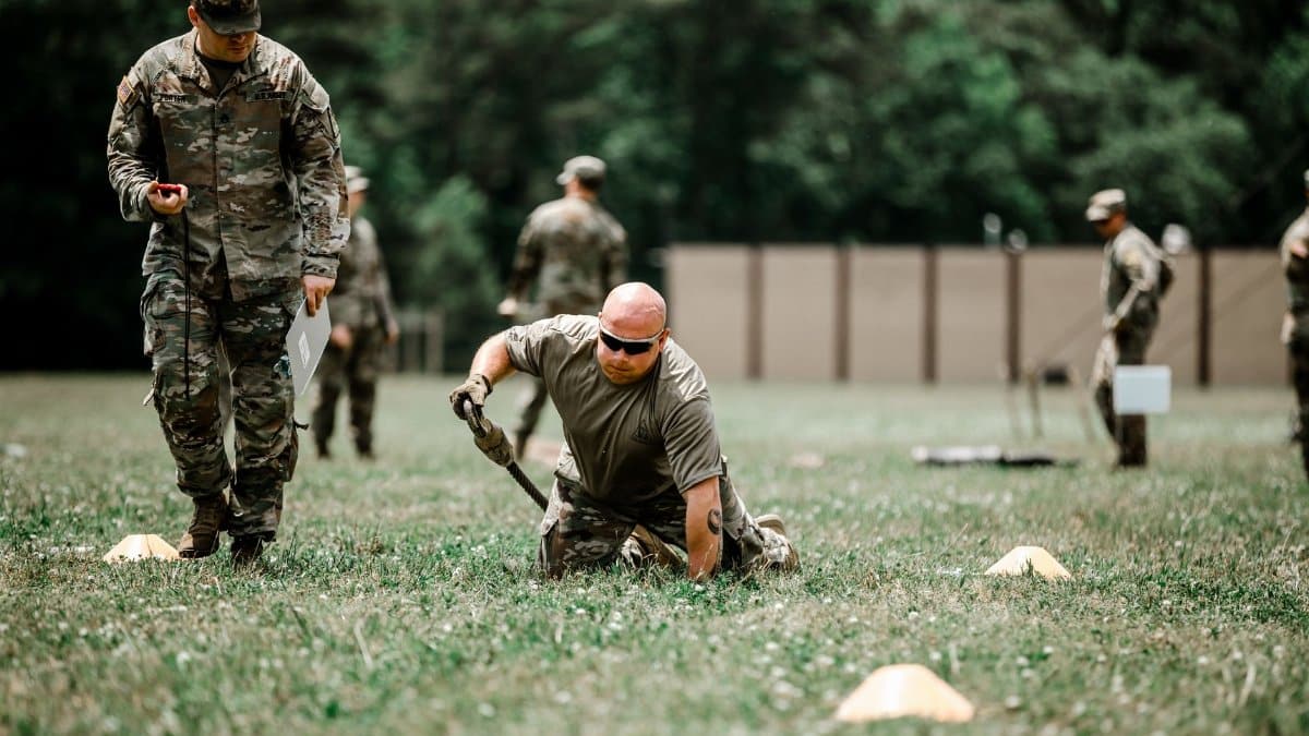 A group of soldiers engaged in a rigorous outdoor military training session in a grassy field.