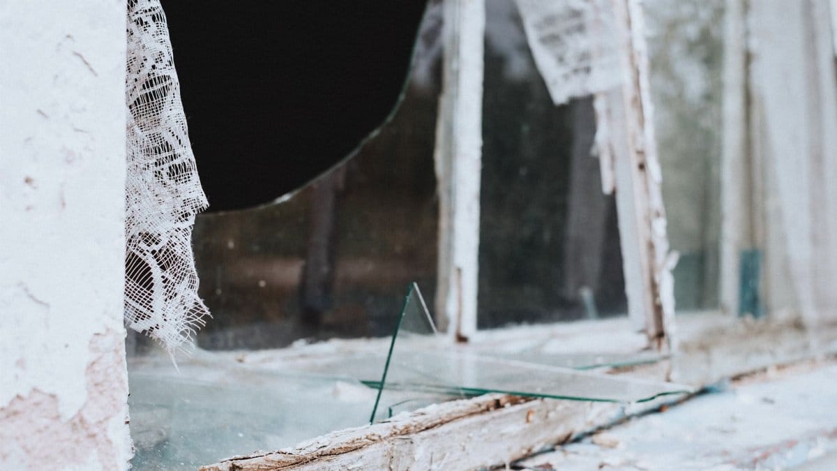 Close-up of a shattered and weathered window in an abandoned building.
