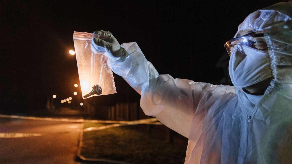 Crime scene investigator examines evidence in a nighttime urban setting.