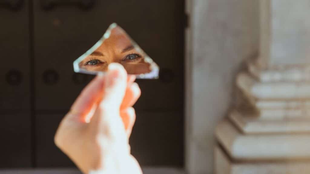 A person's eyes reflecting in a small broken mirror piece held outside in Munich.