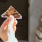 A person's eyes reflecting in a small broken mirror piece held outside in Munich.