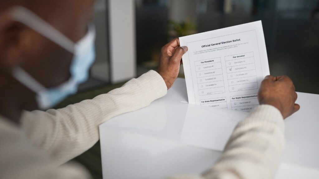 African American man wearing face mask casting a vote with official ballot