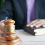 A wooden gavel and legal book represent justice in a court setting, emphasizing order and legal authority.