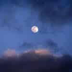 Captivating full moon with dynamic clouds in the twilight sky creating a dramatic scene.