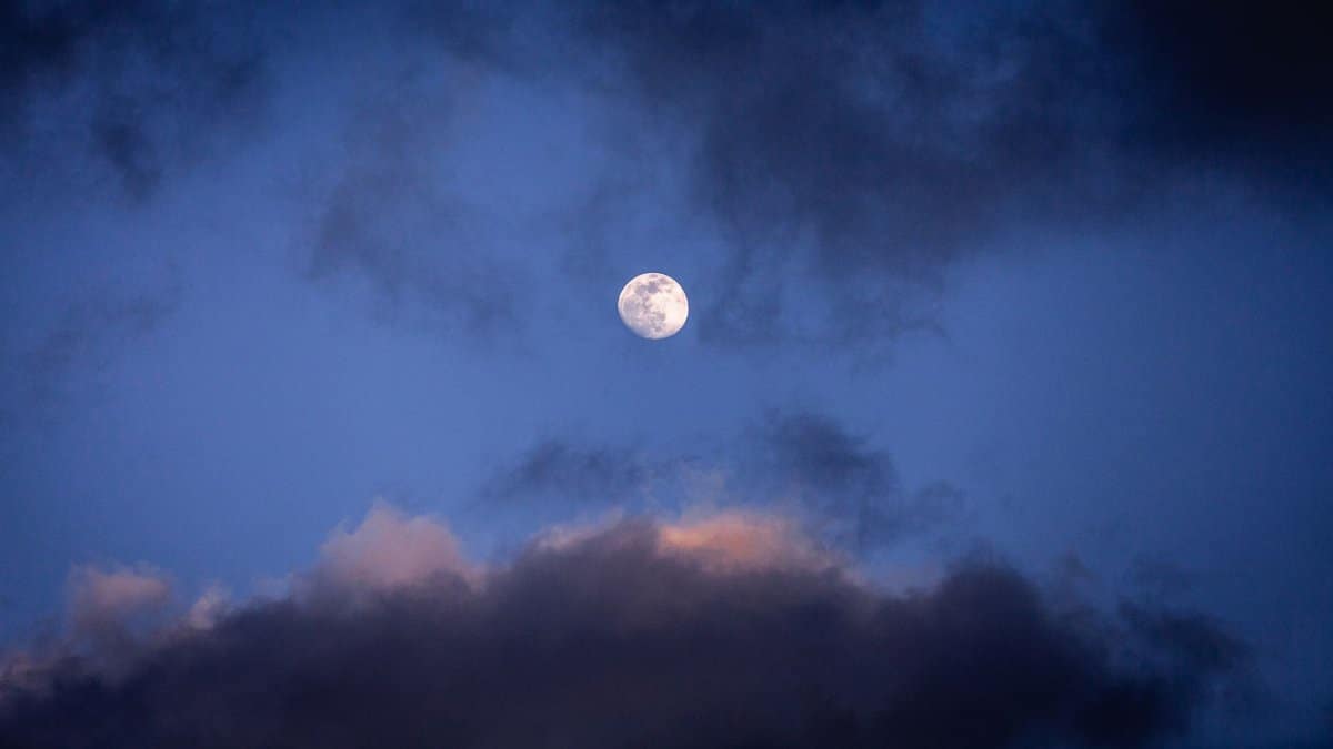 Captivating full moon with dynamic clouds in the twilight sky creating a dramatic scene.