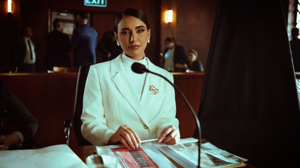 A poised woman in a white suit sits confidently in a courtroom setting, Baghdad.