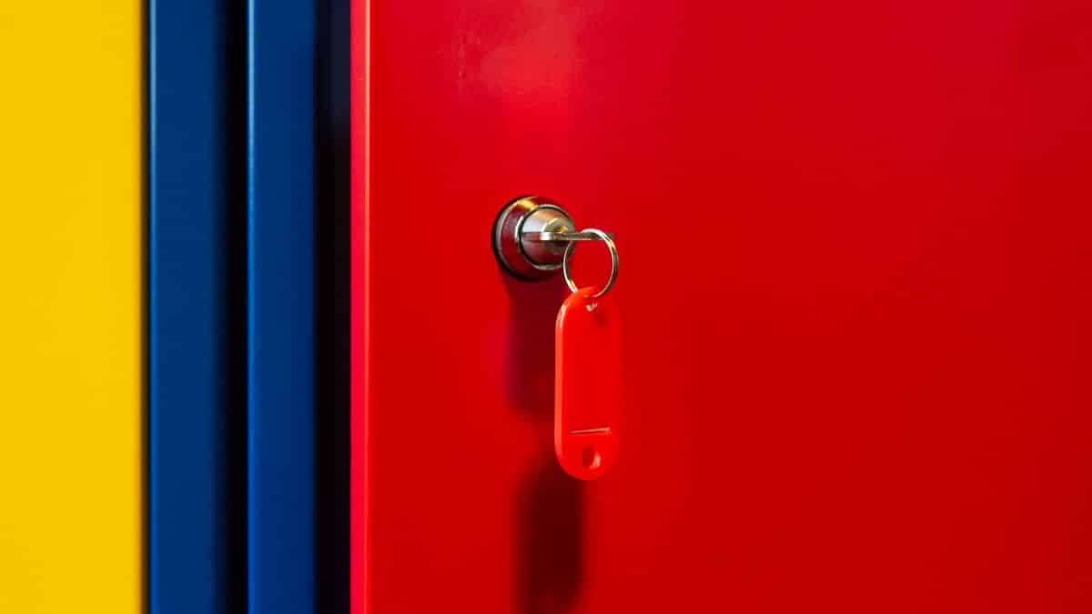 A vibrant image of a red locker door with a key in the lock, featuring bold primary colors.
