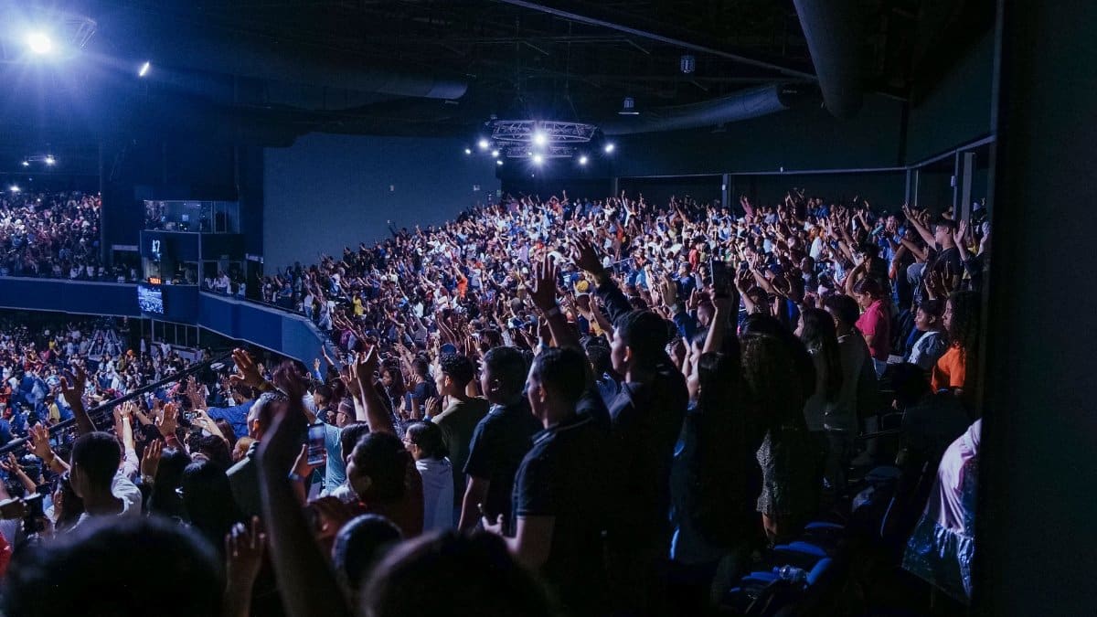 A vibrant audience with arms raised in excitement at a lively indoor concert event.