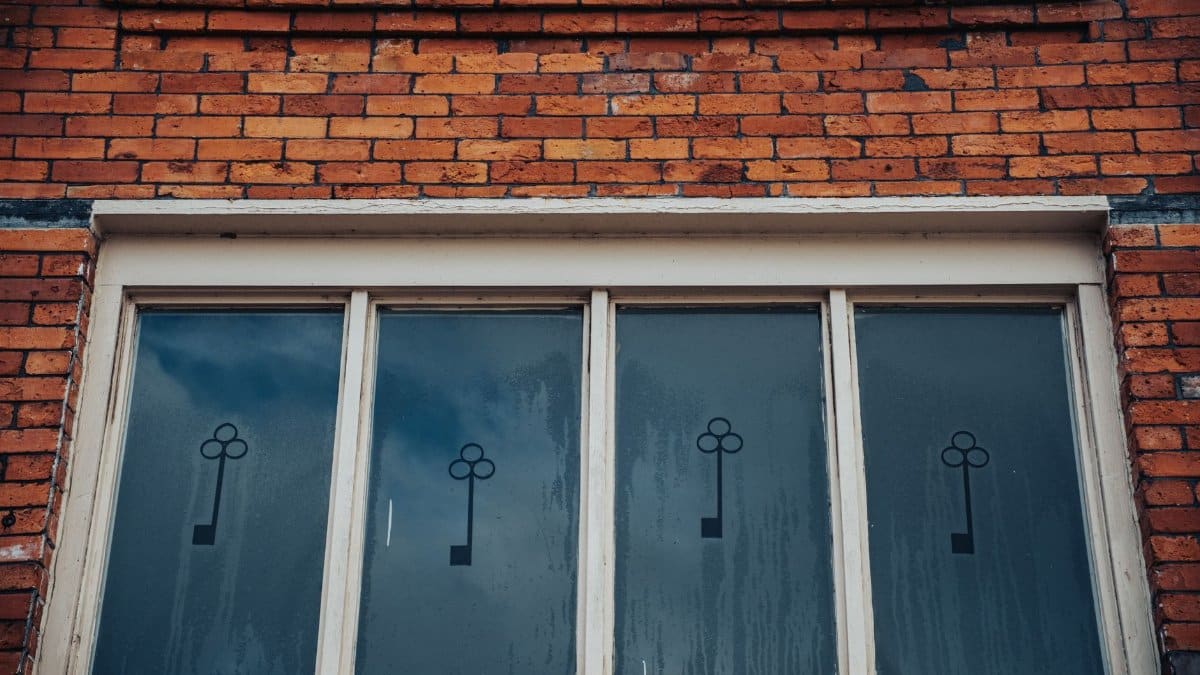 Close-up of a vintage brick wall with decorative frosted glass windows and key motif.
