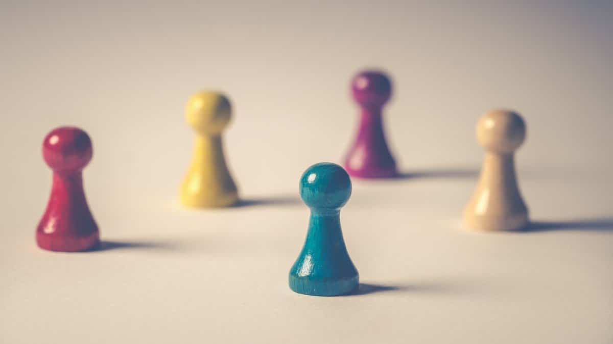 Close-up of colorful board game pawns arranged creatively on white surface.