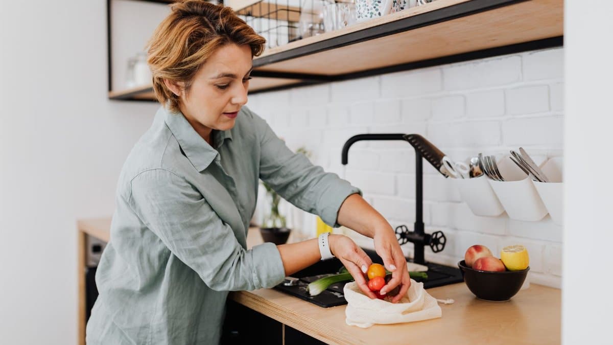 Woman preparing fresh vegetables in a sleek kitchen setting, showcasing culinary activities.