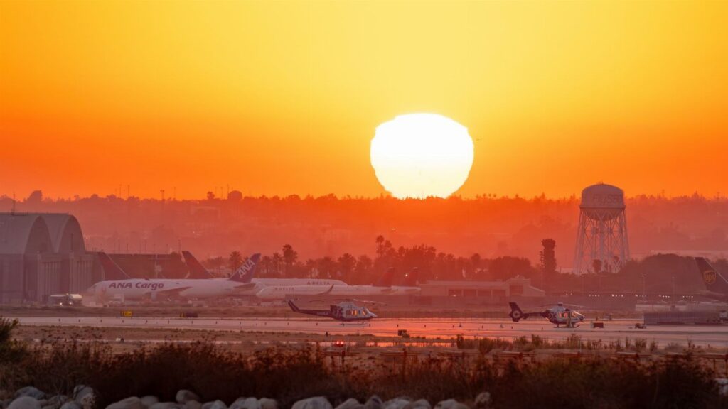 Stunning sunset at San Bernardino Airport with planes and vibrant sky.