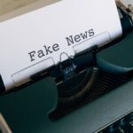 Close-up of a vintage typewriter displaying the words 'Fake News' on paper.