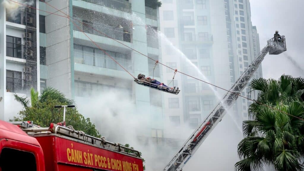 Firefighters conducting a high-rise building rescue with a firetruck and ladder.