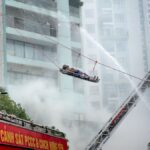 Firefighters conducting a high-rise building rescue with a firetruck and ladder.