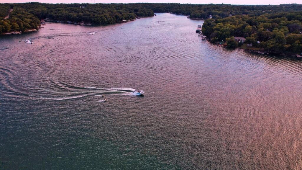 A stunning aerial view of boats gliding on a serene lake in Mound City, Kansas, surrounded by lush greenery.