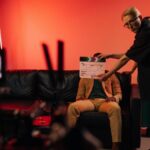 Film production team setting up a scene on an indoor set with dramatic lighting.