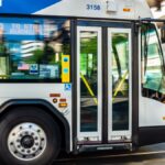 A city bus from TriMet transit system speeds through an urban street during the day.