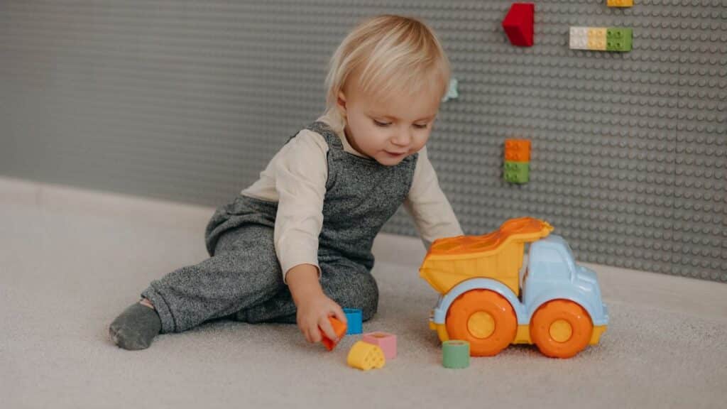Cute toddler engaged with colorful blocks and toy truck indoors.