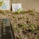 Close-up of a gravestone with handprint tiles, symbolizing remembrance in a memorial park.