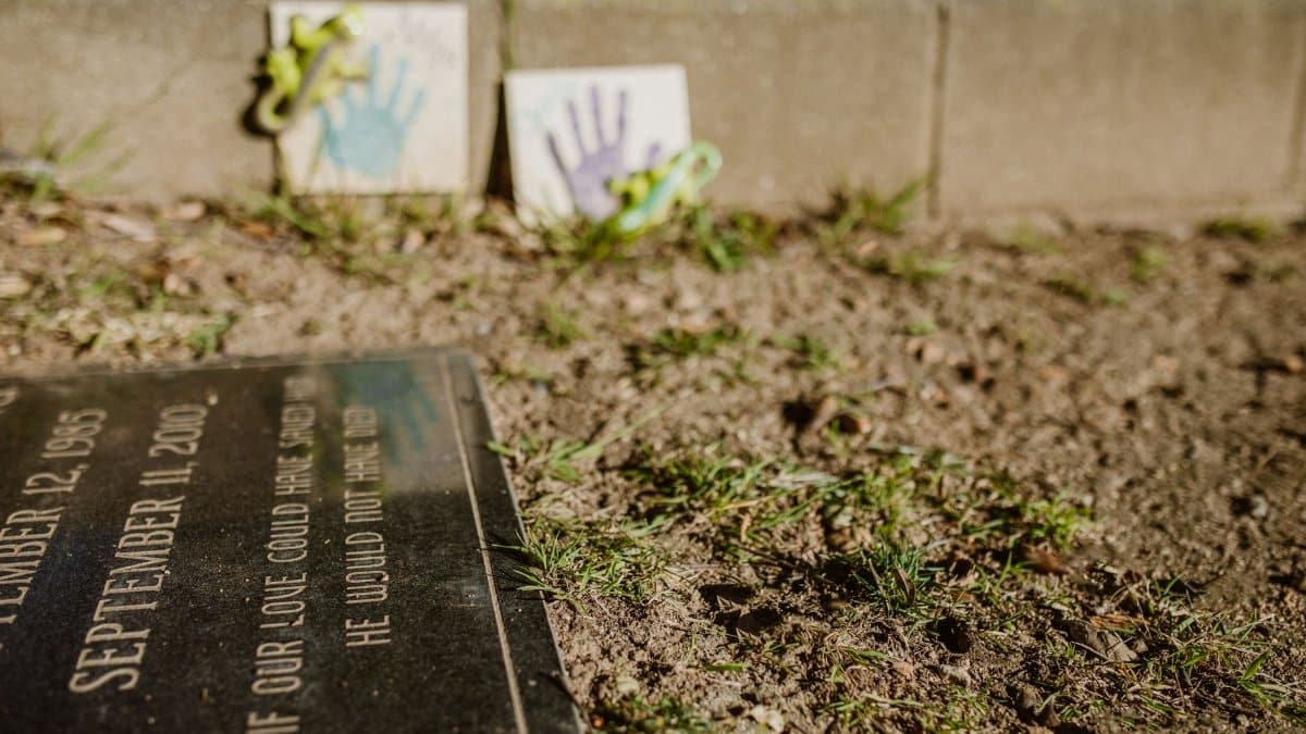 Close-up of a gravestone with handprint tiles, symbolizing remembrance in a memorial park.