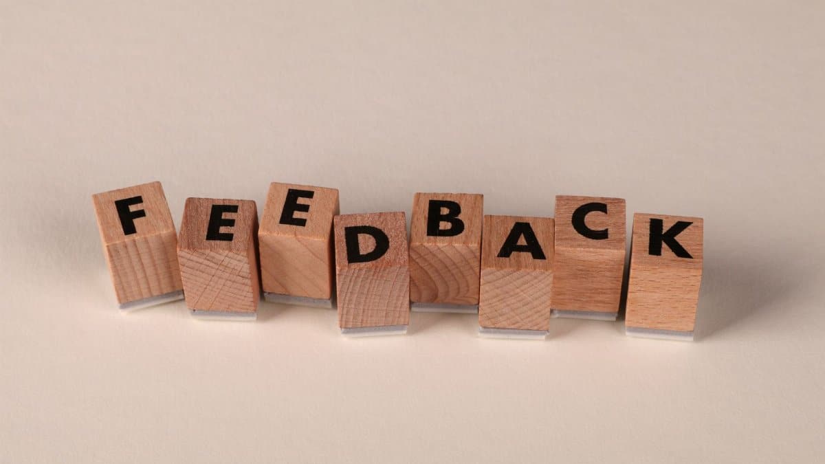 Wooden letter blocks arranged to spell 'FEEDBACK' on a neutral background. Ideal for communication concepts.