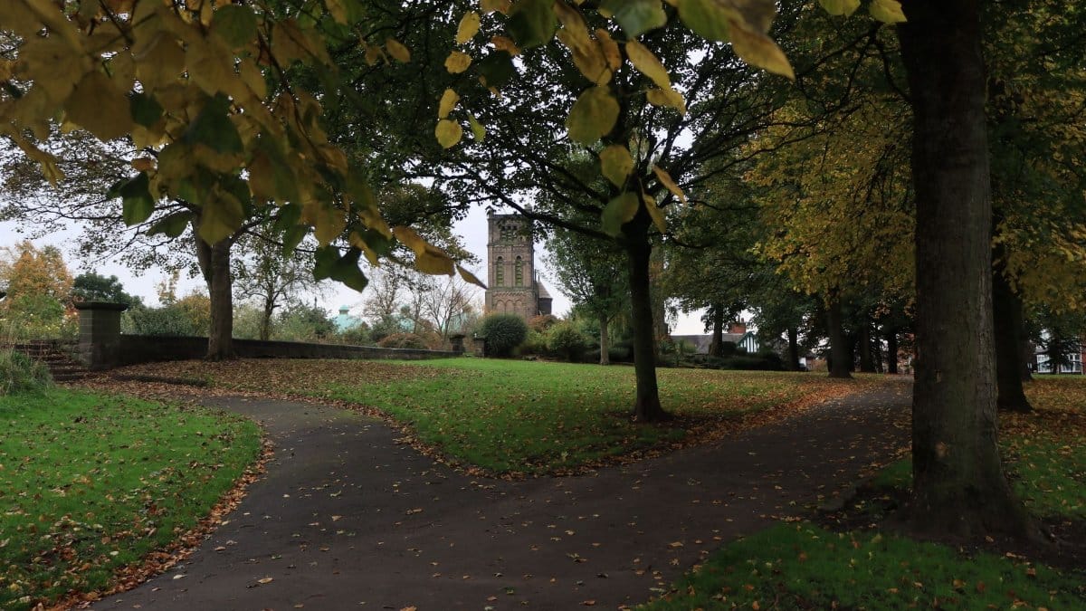 Charming autumn scene with pathways and historic church tower in an English park.