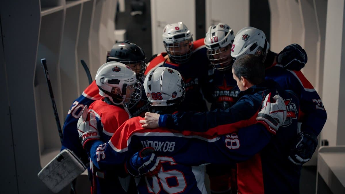Team of young hockey players in locker room huddle, building team spirit before game.