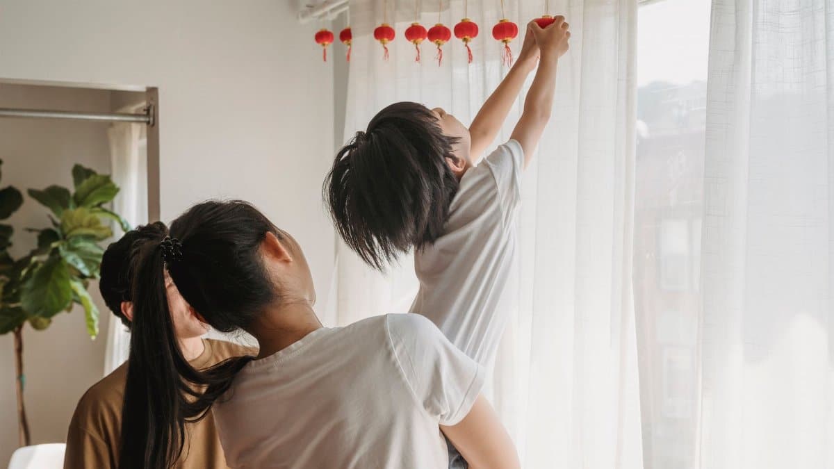 Family decorates with red lanterns indoors, celebrating a festival together.
