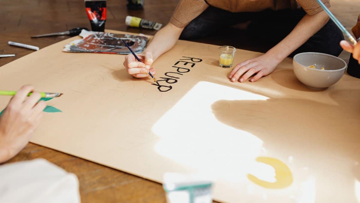 Creative hands painting on paper, showcasing an artistic collaboration indoors.