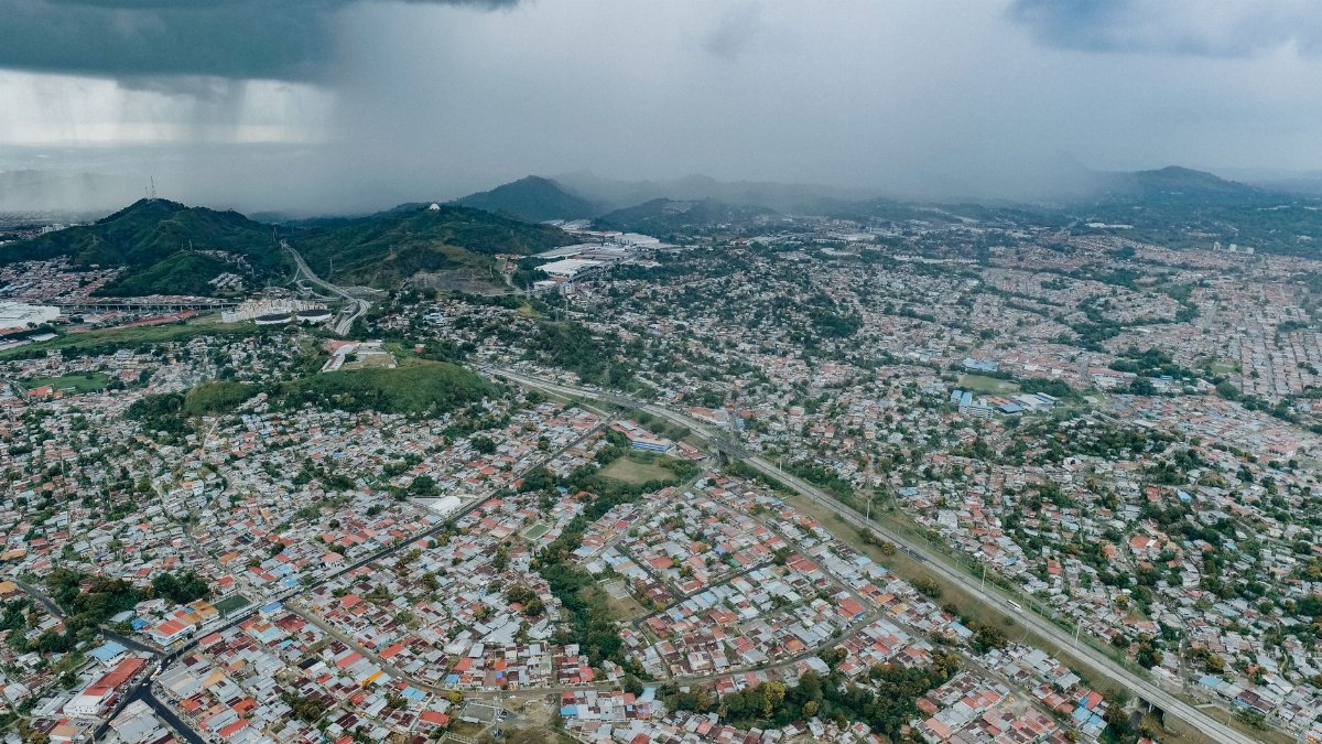 Aerial view of Panamá City showcasing extensive urban sprawl beneath a dramatic stormy sky.