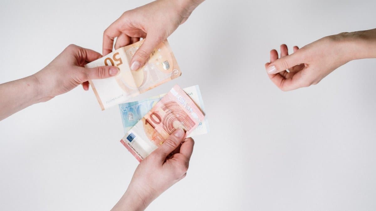 Close-up of hands exchanging euro banknotes, symbolizing currency trade and financial transactions.