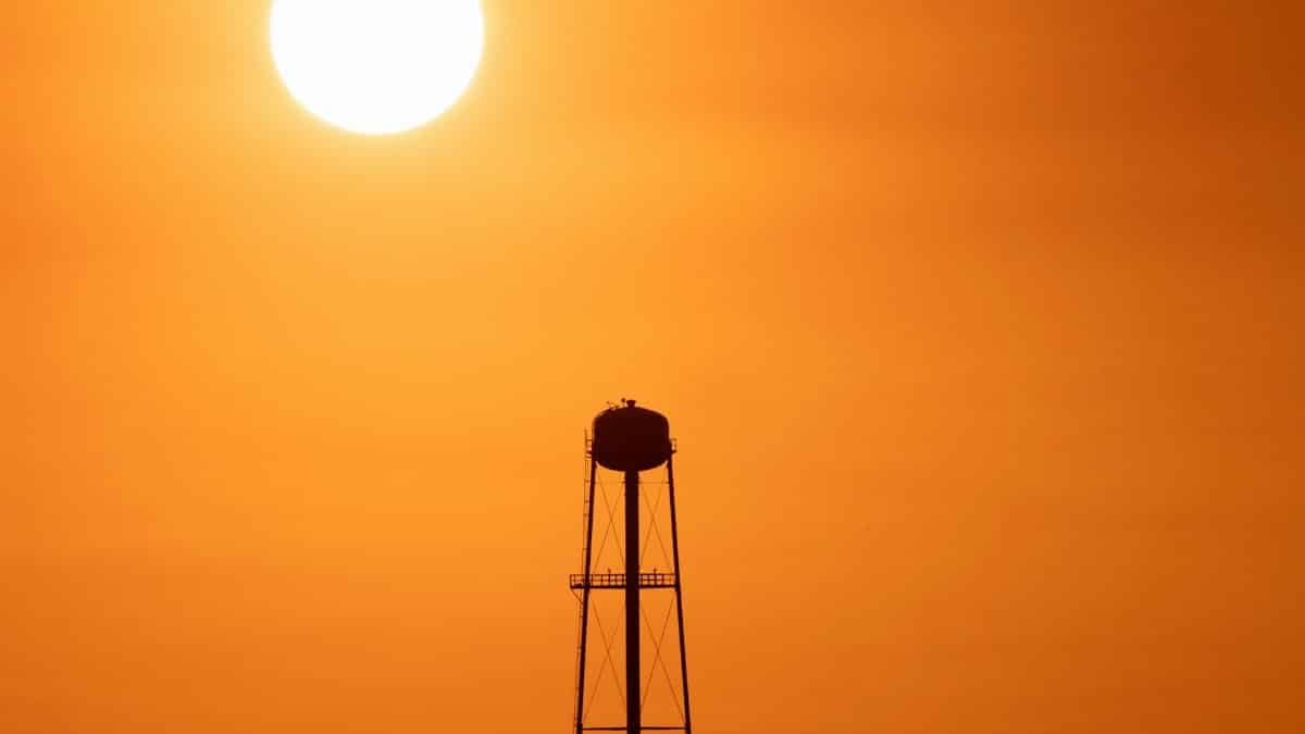A striking sunset silhouette of a water tower against a vivid orange sky in Mather, CA.