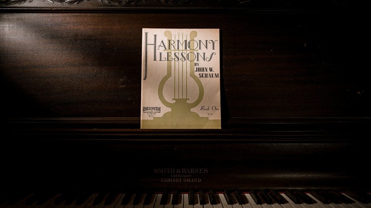 Dark, vintage piano with 'Harmony Lessons' sheet music, offering a classic and artistic ambiance.