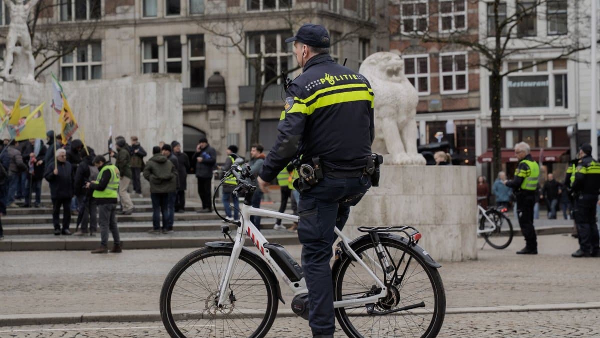 A police officer on a bike monitors a public demonstration in a city square.