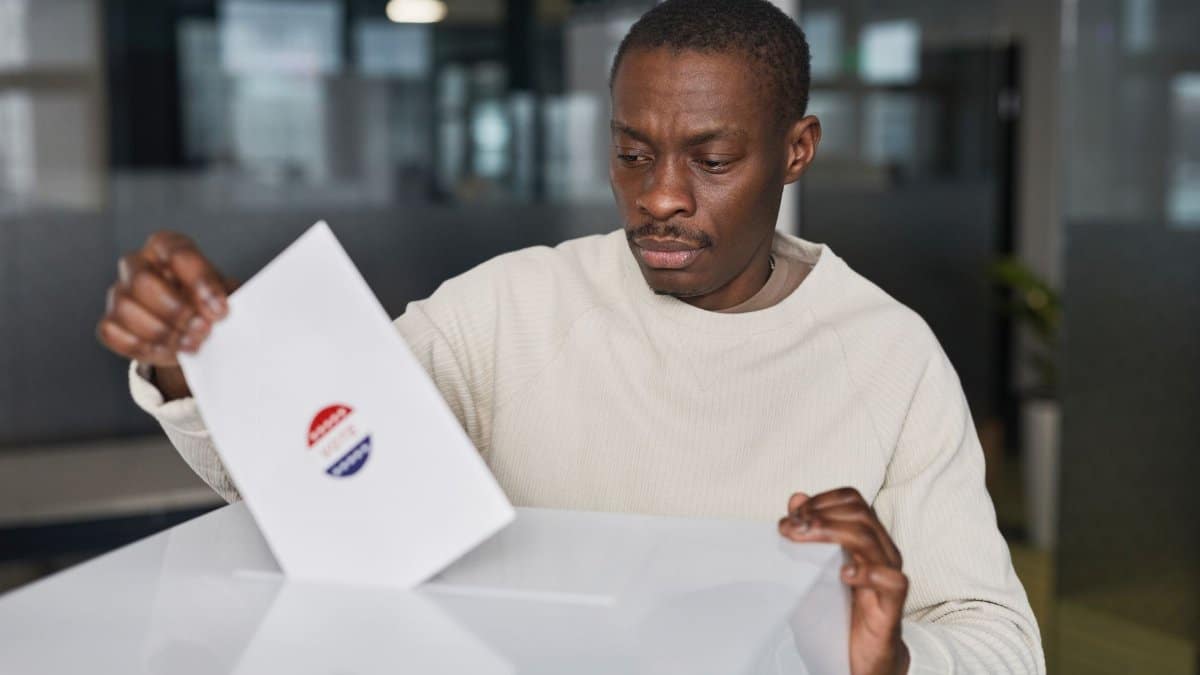 A man casts his vote in an office environment, focused and serious.