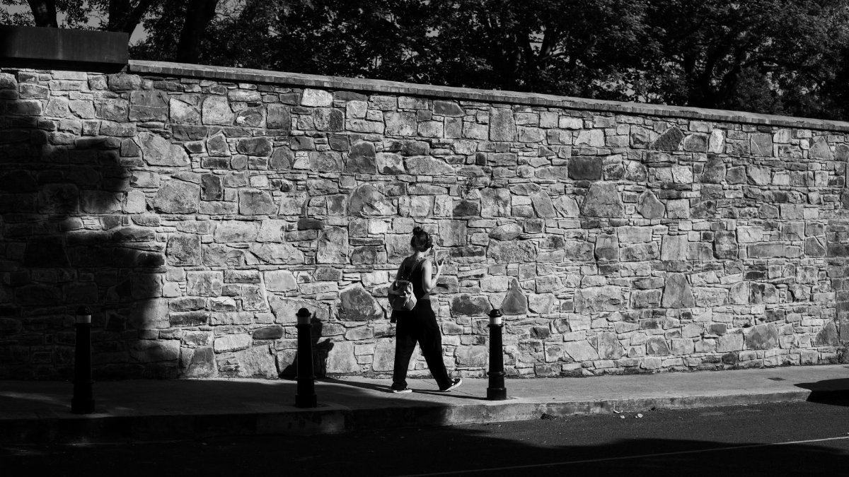 Black and white photo of a woman walking in Dublin, capturing urban life and texture.