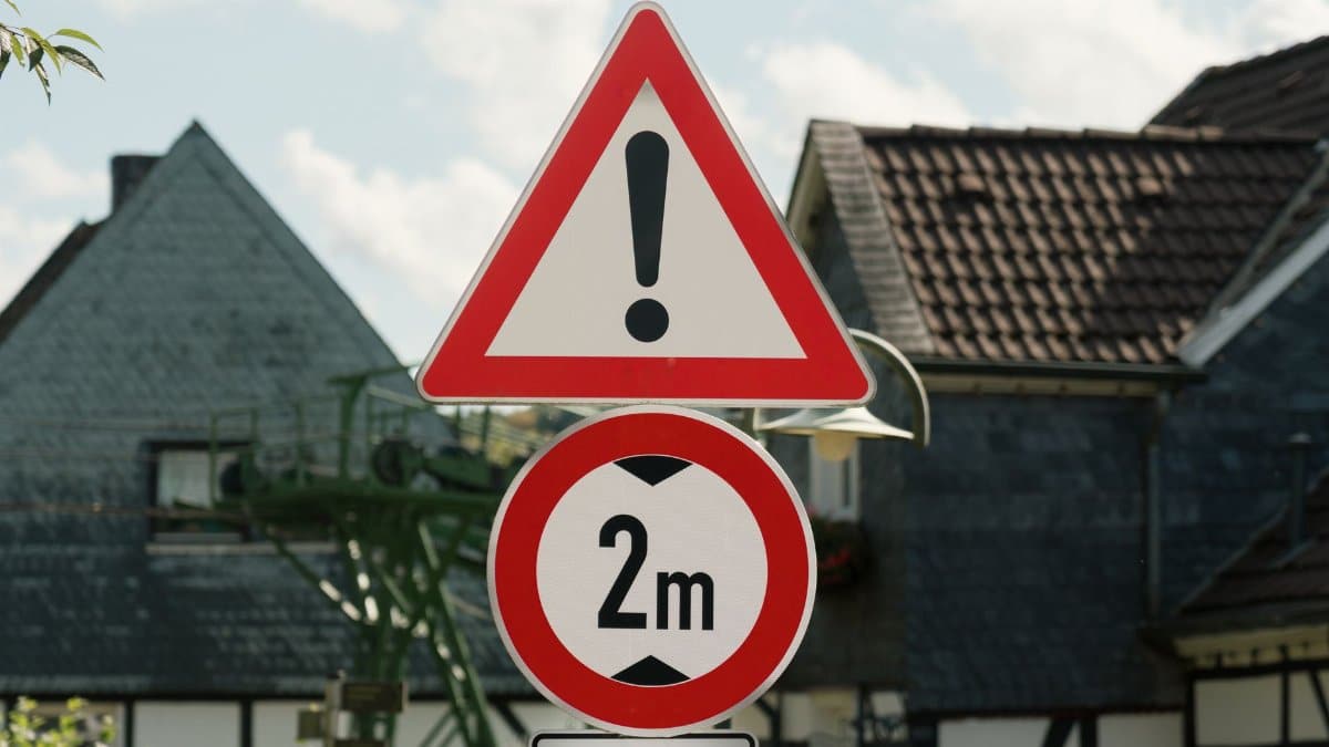 Traffic signs in a rural German village indicating warning and a 2m distance restriction.