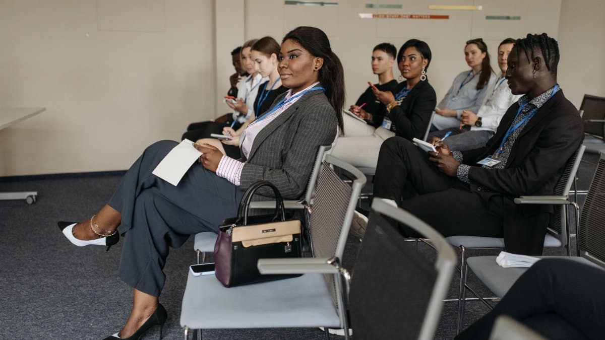 A diverse group of adults engaged in a business seminar, showcasing active listening and participation.