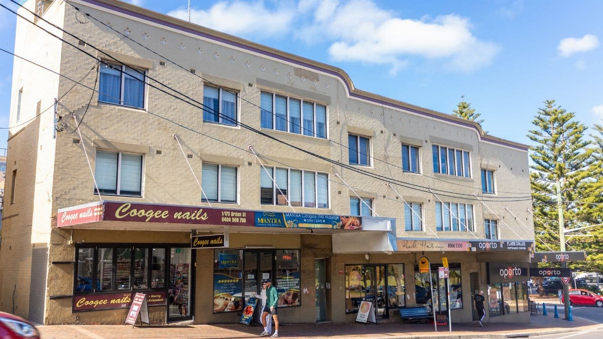 Street view of Coogee shops and apartments under a clear sky featuring local businesses.