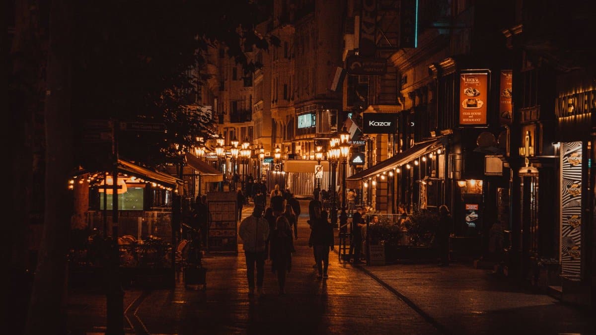 Captivating nighttime scene of an illuminated alley in Budapest, bustling with people.