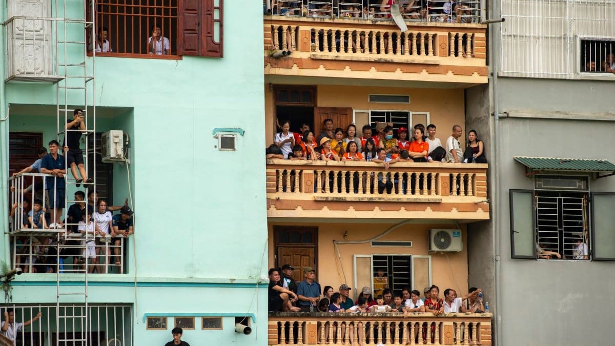 Group of people watching an event from balconies of apartment buildings in Lào Cai, Vietnam.