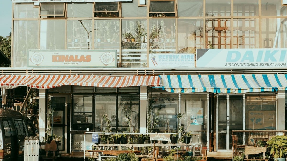 Charming street scene featuring local shops with colorful striped awnings and outdoor plants.