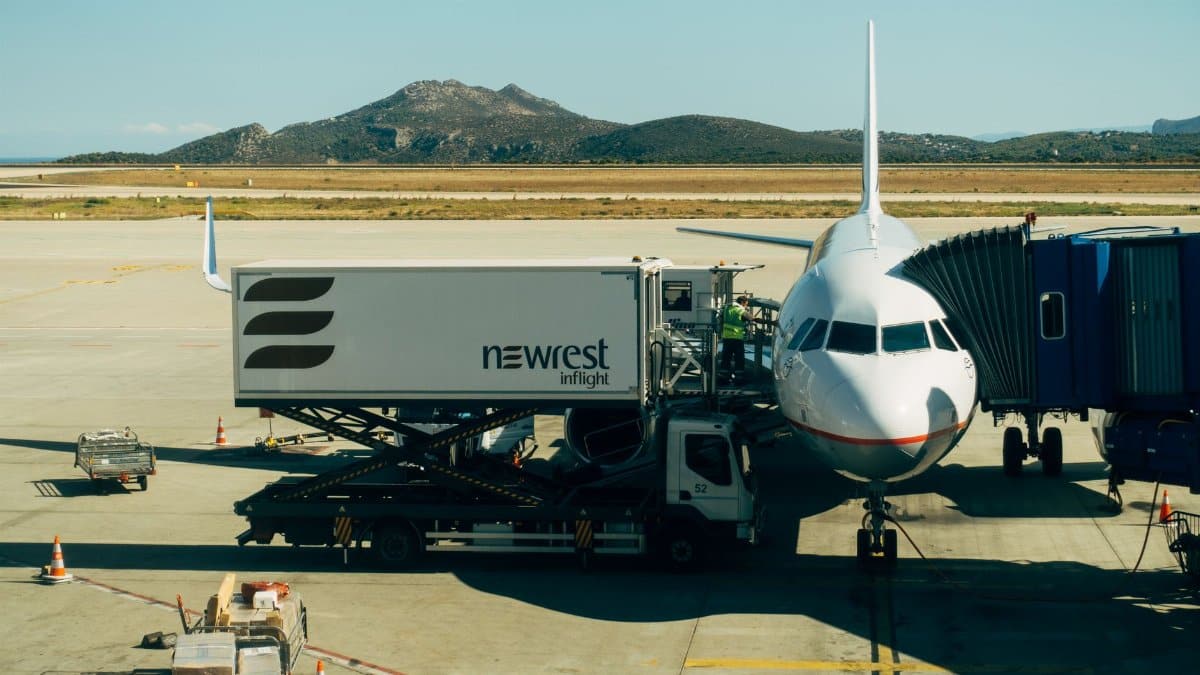 A commercial airplane being serviced at an airport with fueling and loading equipment.
