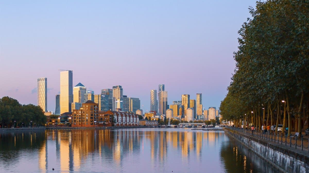 Beautiful skyline of a modern city at sunset, reflecting on a calm river.