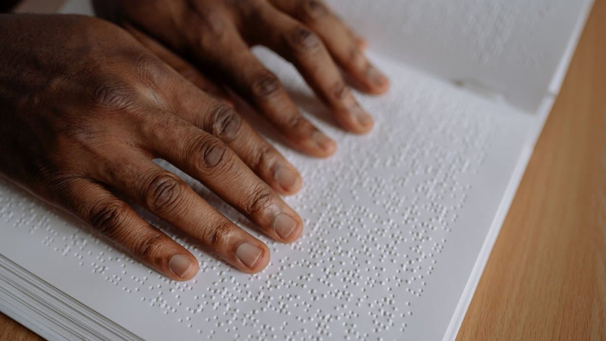 Close-up of hands reading Braille text on paper. Education and inclusivity concept.