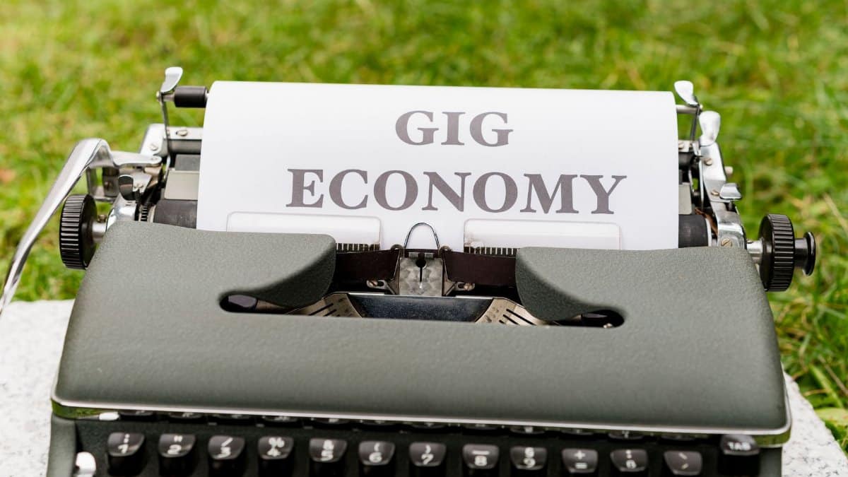 A vintage typewriter with 'Gig Economy' paper in an outdoor setting.