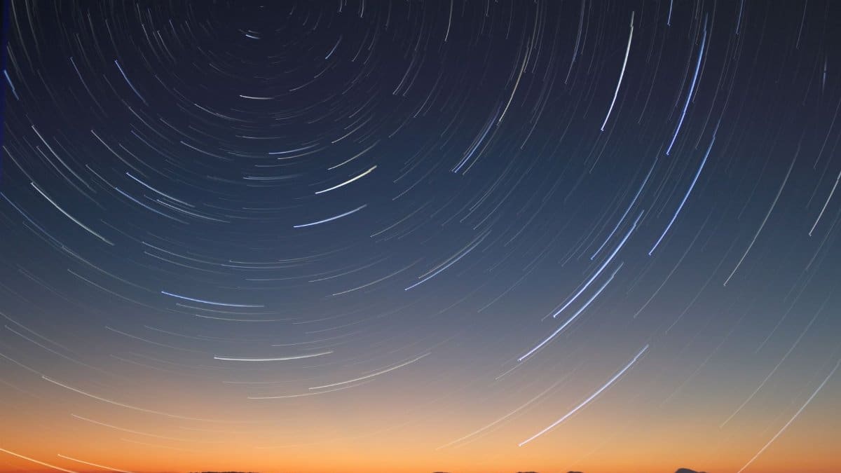 A stunning long exposure of star trails over the ocean horizon at twilight.